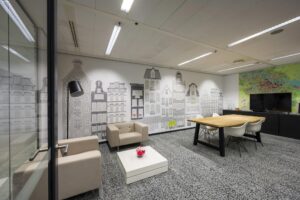 Modern meeting room with a wall mural of Amsterdam canal houses and a large map next to a flat-screen TV.